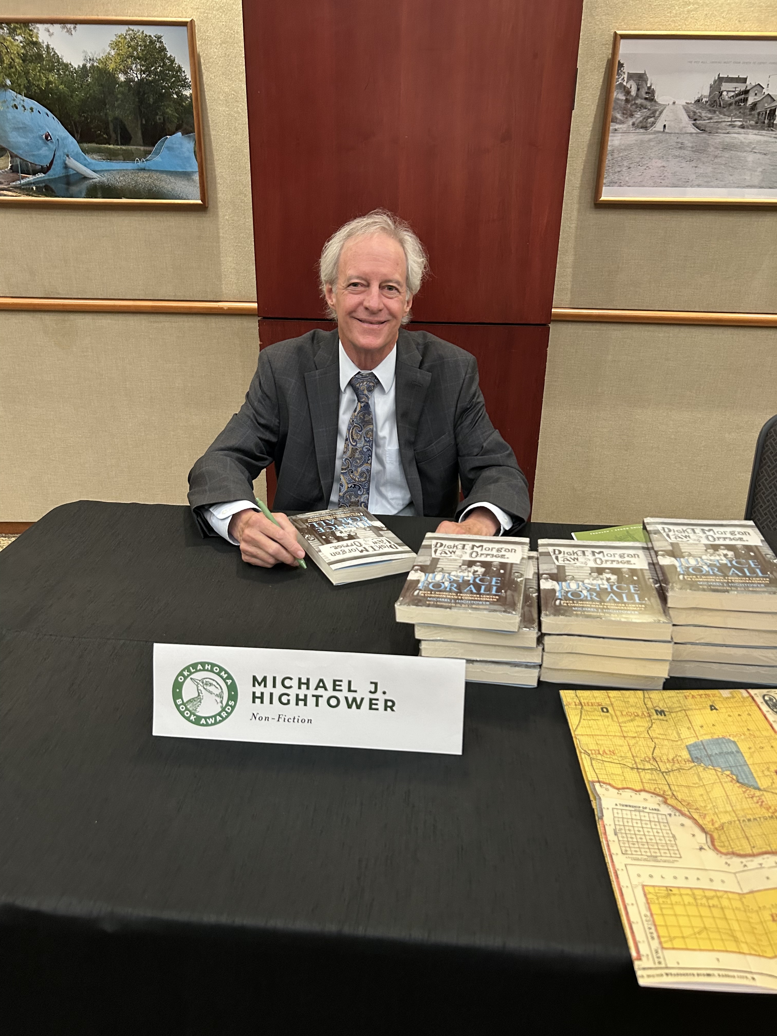 Michael at a table signing copies of Justice for All at the awards ceremony